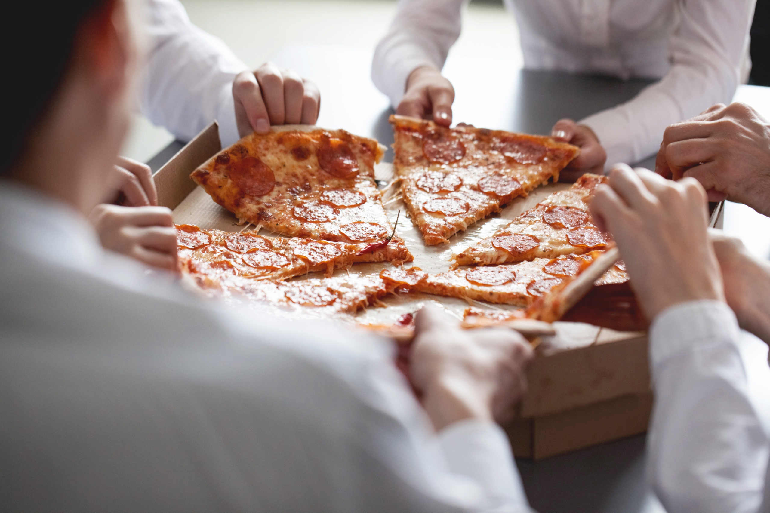 Business team eating pizza in office sitting around the table